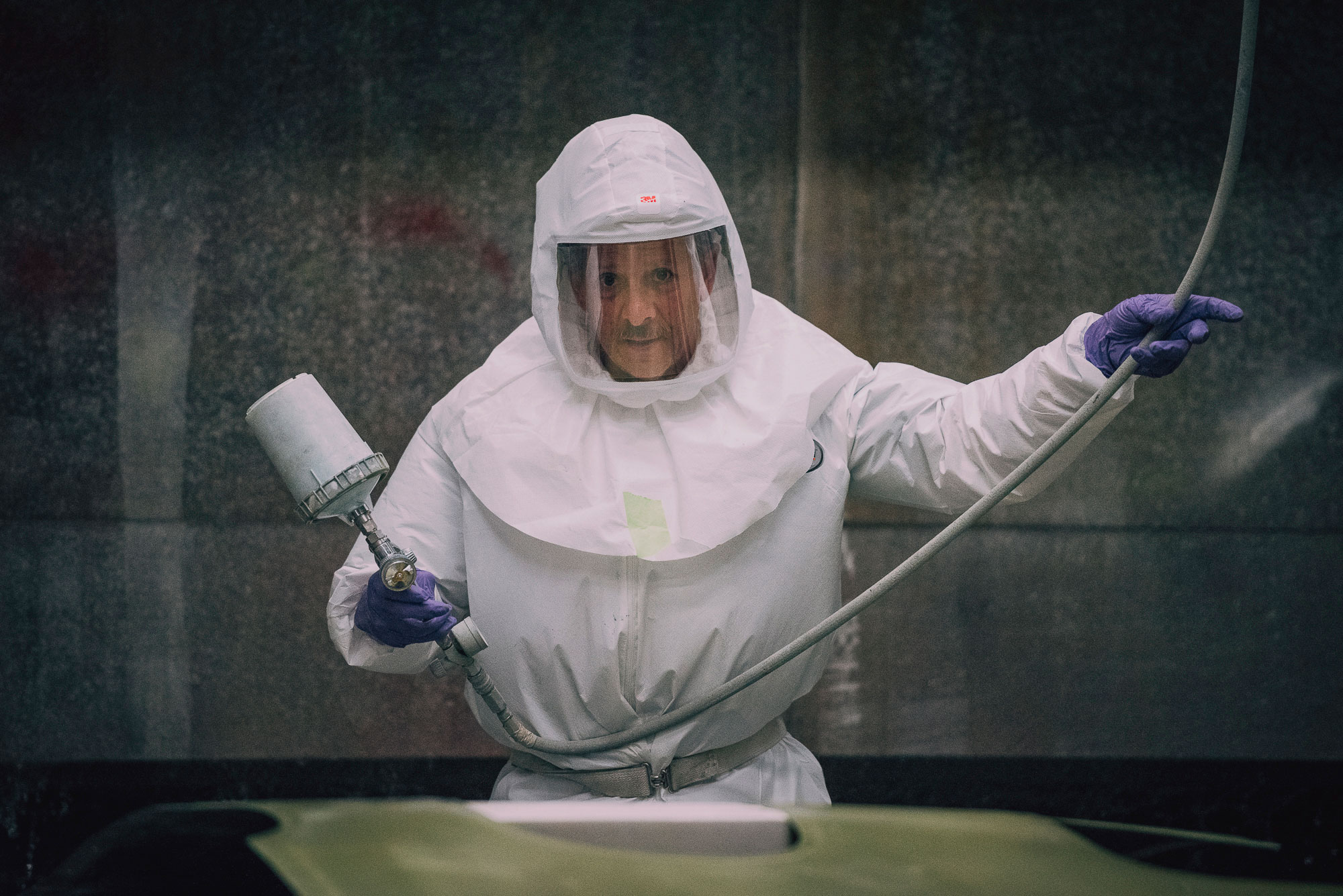 Man in hazmat suit holds a maintenance tool.