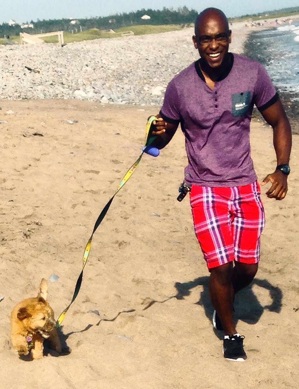 Man running with dog on beach.