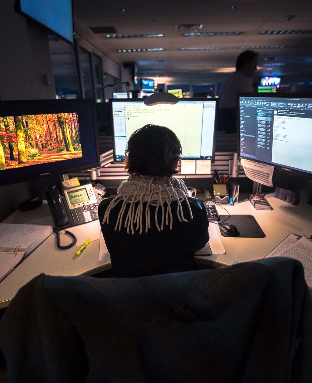 Woman sits at a computer with 2 screens.